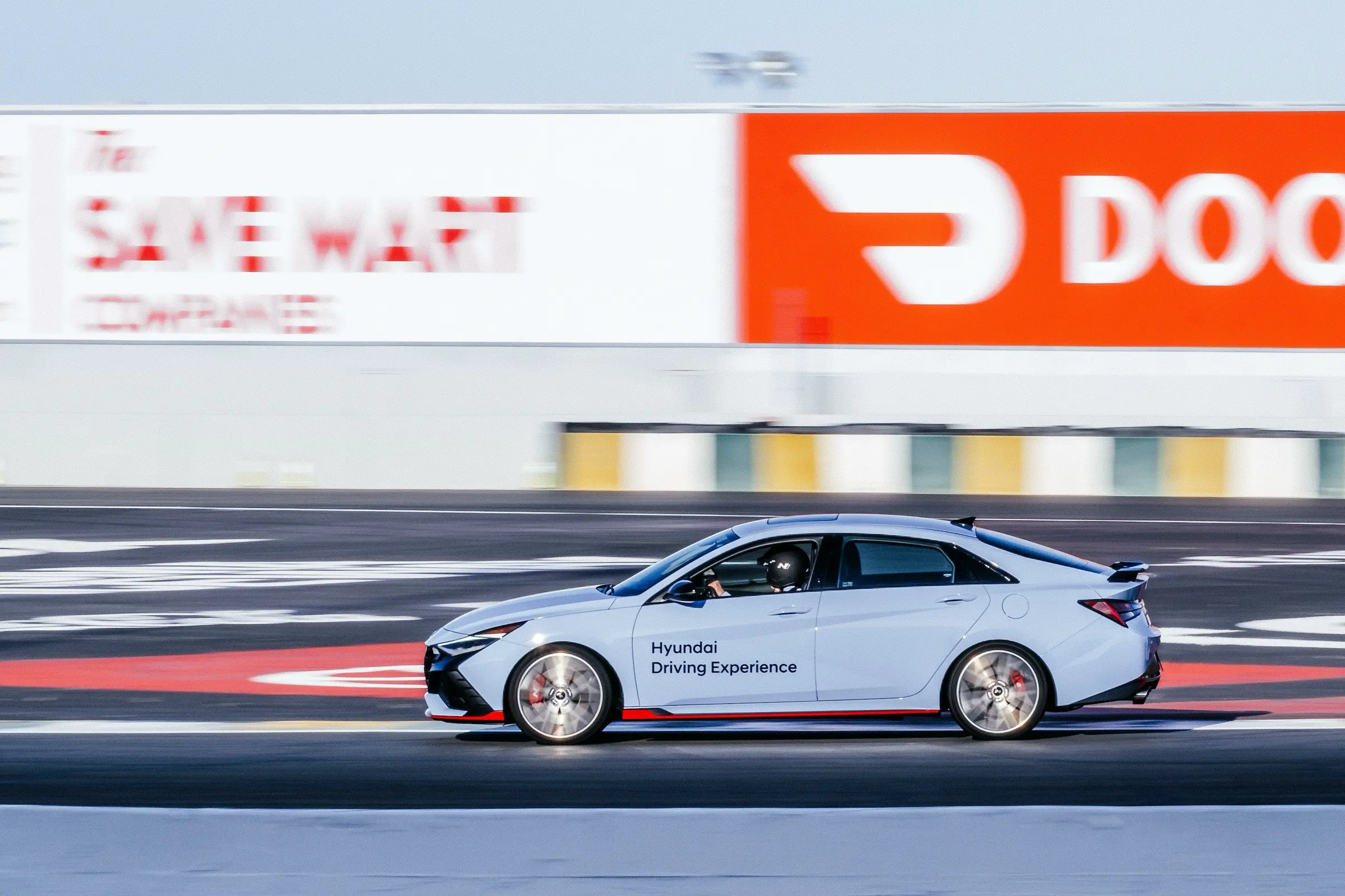 Ein hellblauer Hyundai Elantra N, der schnell auf der Zielgeraden fährt.