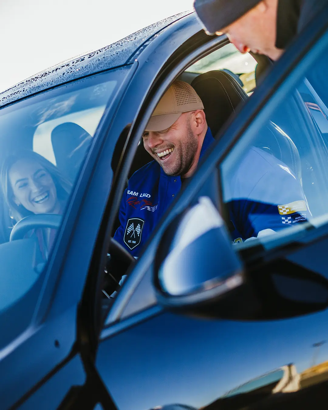 Ein Mann und eine Frau, die vom Instructor im Auto sitzend mit den Funktionen vertraut gemacht werden.