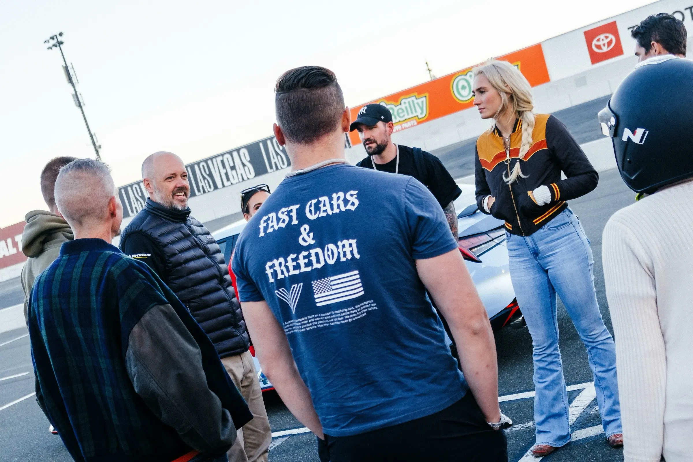 8 teilnehmende und ein Instructor stehen vor einem Fahrzeug und machen eine Nachbesprechung zur vorangegangenen Übung.