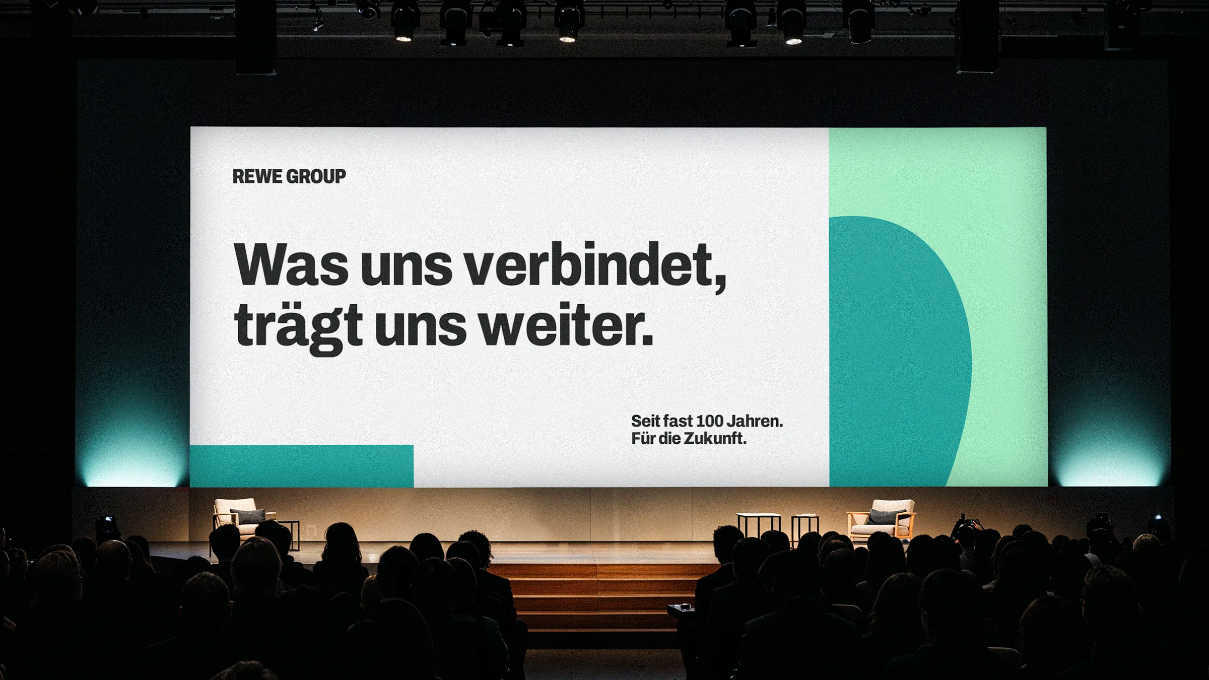 Große Bühnenpräsentation im neuen REWE GROUP Corporate Design vor Publikum.